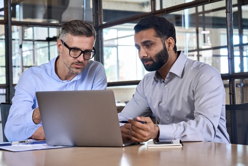 Professionals collaborating over a laptop, showcasing Confluence Advisors' sell-side advisory services.