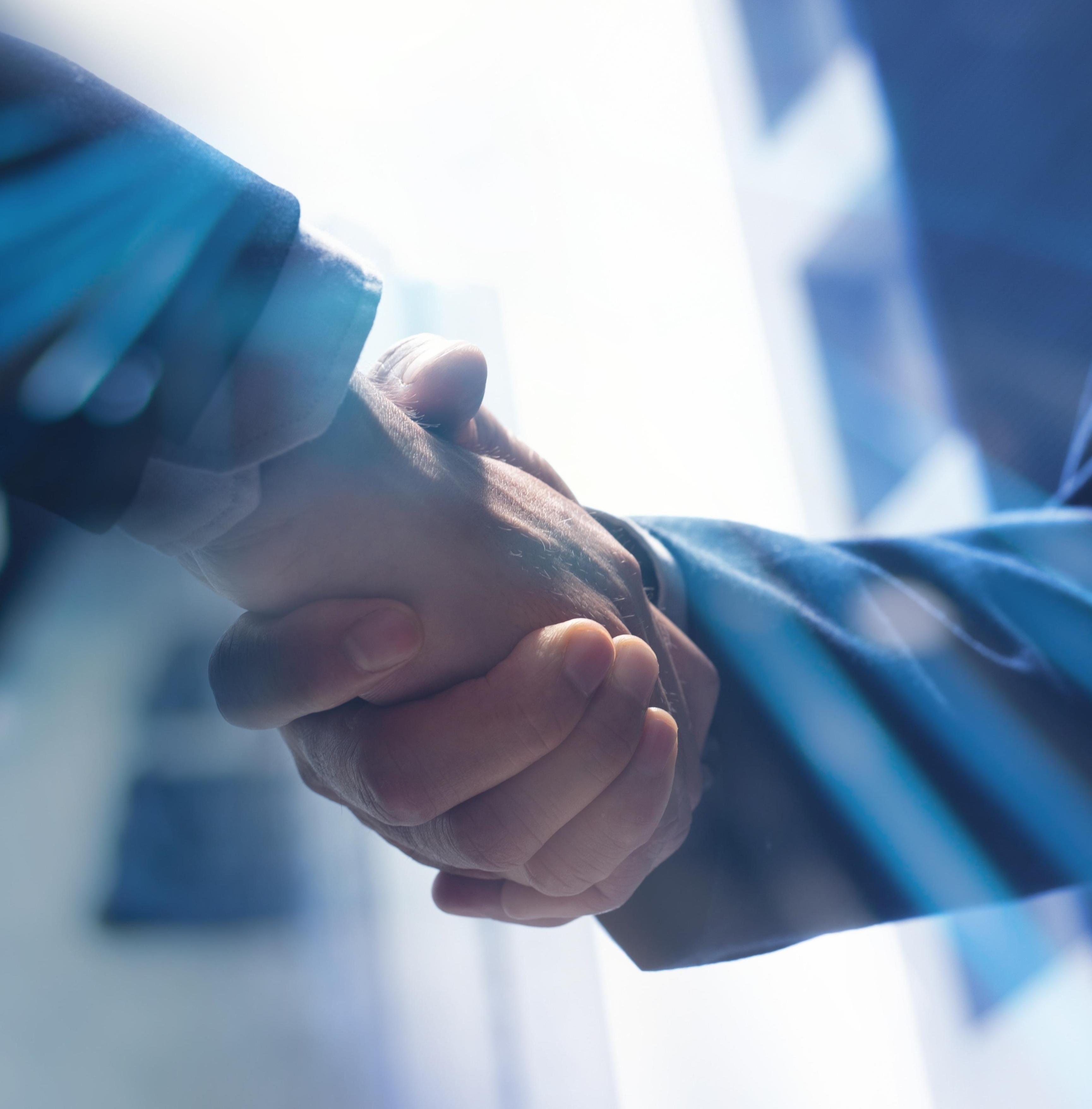 Handshake in an office setting, representing Confluence Advisors' management buyout expertise.